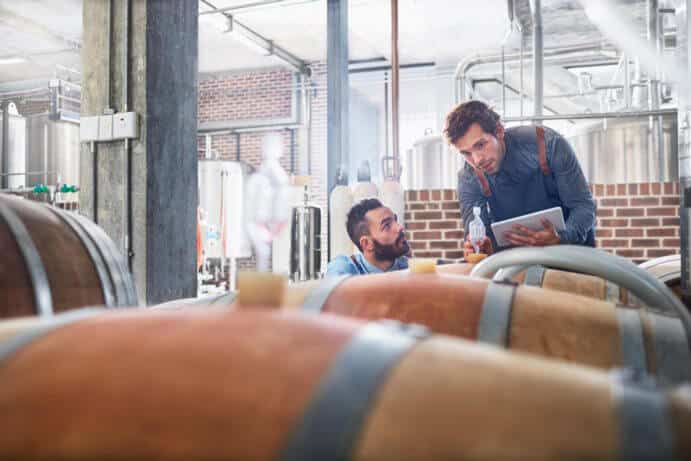 Male winemakers with digital tablet checking wood casks. Image shot 2016. Exact date unknown